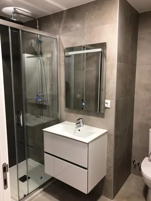 Casa de banho com base de duche, divisória de vidro e móvel suspenso branco
